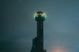 The iconic Reunion Tower glowing vividly during the night in Dallas, Texas.
